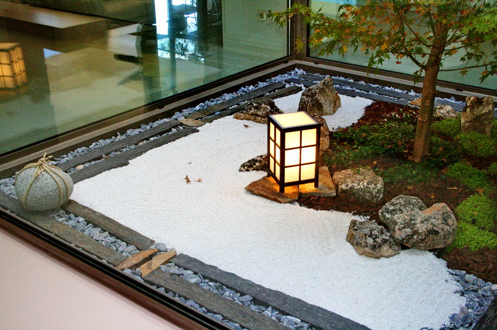 Composición de grava blanca, piedra natural y vegetación en jardín zen