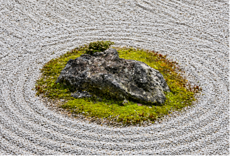 Roca cubierta de musgo sobre grava rastrillada en un jardín japonés