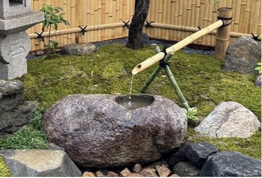 Tsukubai de piedra con caña de bambú en un jardín japonés